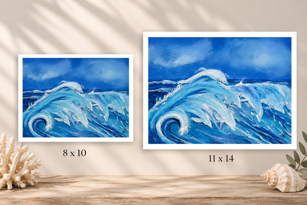 Two framed art prints depicting a blue ocean wave scene, shown side by side on a wooden surface with decorative seashells and leaves. The left print is labeled 8 x 10 and the right print is labeled 11 x 14.