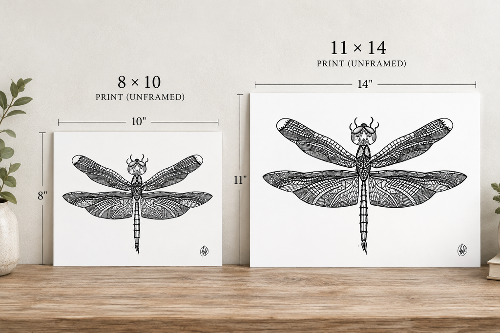 Two framed-style art prints with dragonfly illustrations shown on a wooden surface against a light wall, with size labels above each print: 8 x 10 inches and 11 x 14 inches print (unframed).