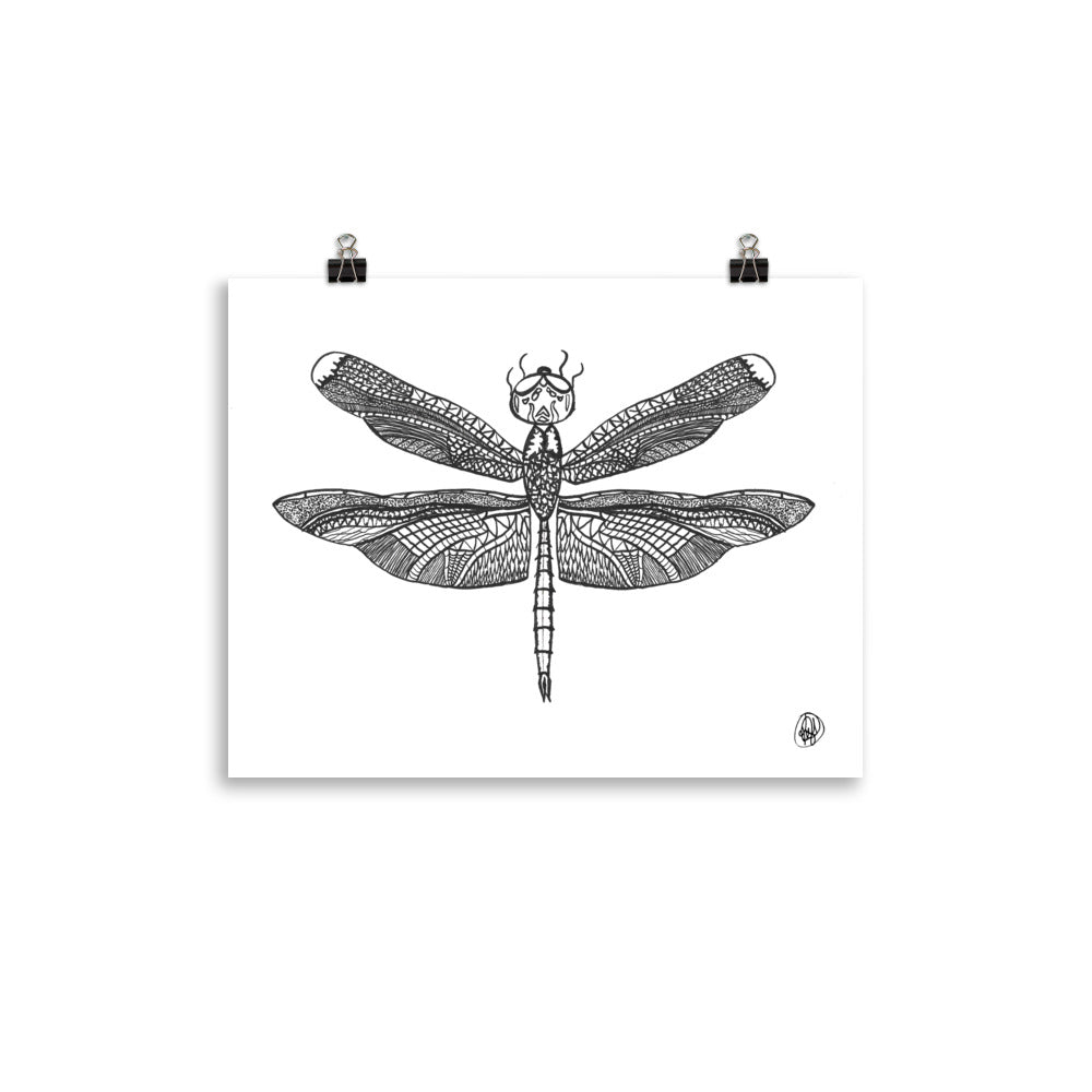 A black and white dragonfly art print clipped at the top with two black binder clips against a solid white background.
