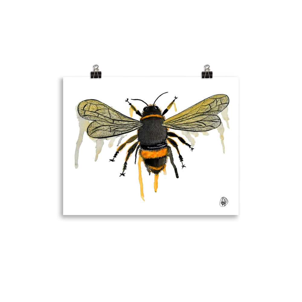 A square art print featuring a detailed watercolor illustration of a bumblebee, shown hanging from two black binder clips against a clean white background.