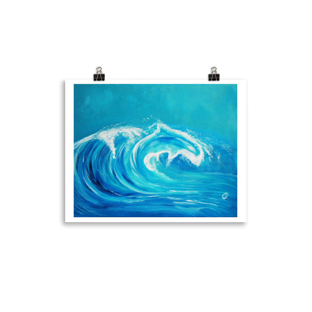 A square art print depicting a curling ocean wave in shades of blue and white, shown hanging from two black binder clips against a clean white background.