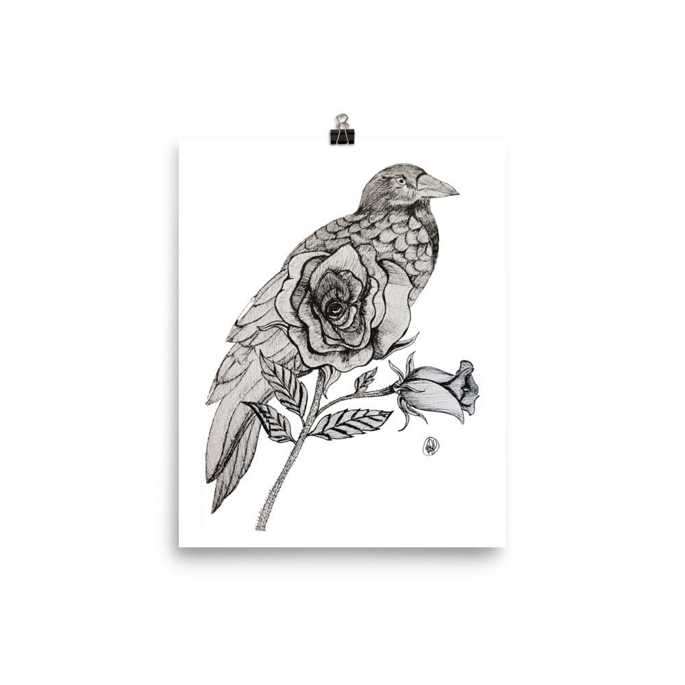 A black and white art print featuring a detailed illustration of a bird perched on a rose, shown hanging from a black binder clip against a white background.