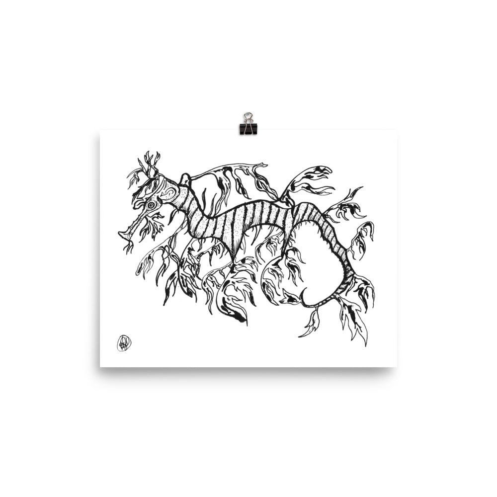 A black and white line art print depicting a stylized sea creature or kelp-like figure, shown hanging from a black clip against a clean white background.