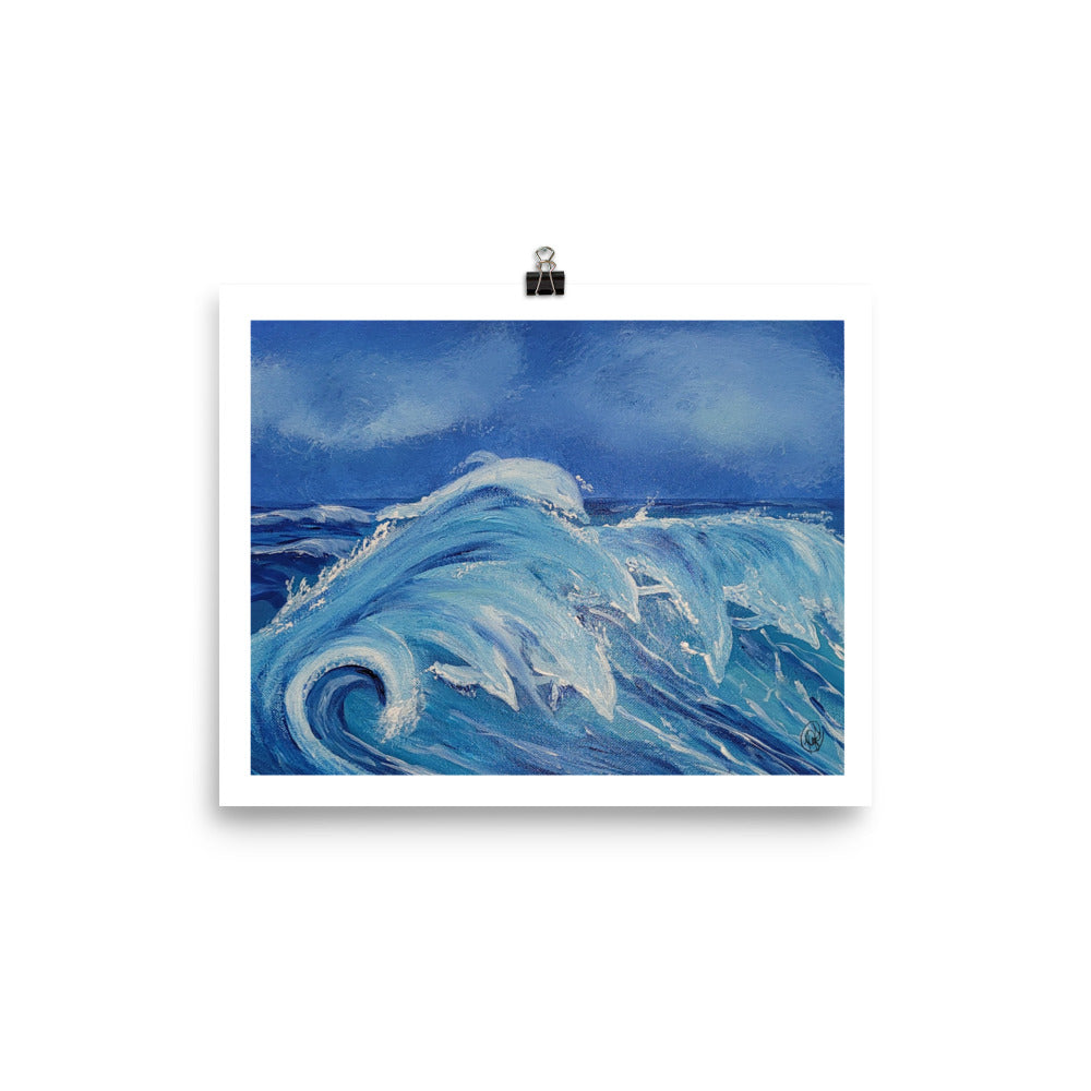A square art print depicting a powerful blue ocean wave with white foam under a deep blue sky, held by a black binder clip against a clean white background.